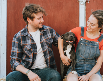 A man and woman happily hold their dog.